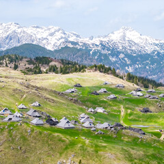 Fototapeta na wymiar Aerial panorama of Velika Planina alpine village with traditional wooden huts scattered across green hills. Perfect spring eco-tourism destination in Slovenia