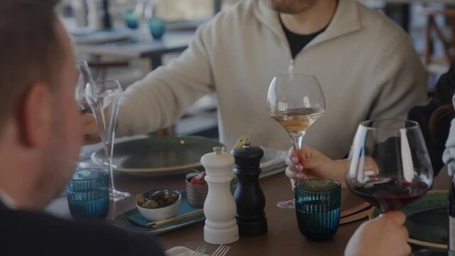 A woman is holding a wine glass and smiling. A man is sitting next to her. They are at a restaurant