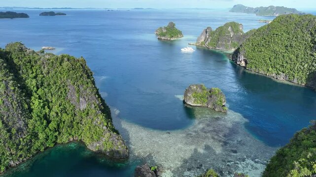 Rugged limestone islands rise from the seascape in Misool, Raja Ampat, Indonesia. This area is known as the heart of marine biodiversity and is a popular destination for diving and snorkeling.