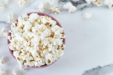Popcorn in a bowl on white marble background. Top view. Copy space.