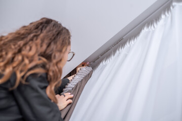 The designer hangs white tulle and a thick gray curtain on the window