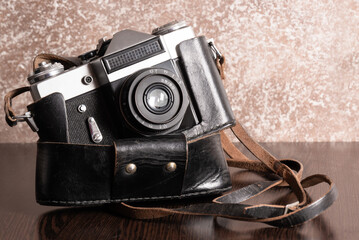 The Classic Vintage Old shabby Photo Camera in a dark brown case open lens brown natural leather Strap Wooden table 