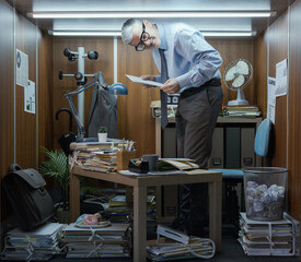 Tall businessman working in a small office