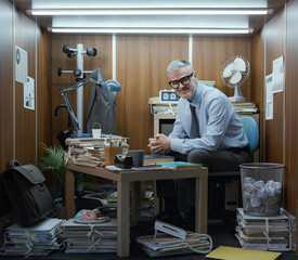 Portrait of a funny businessman working in a tiny messy office