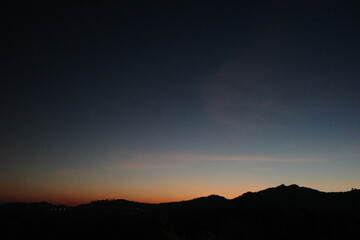 Tranquil twilight over mountain silhouettes with a subtle orange and blue gradient in the sky. A peaceful, minimalist nature scene ideal for backgrounds, meditation, or evening-themed projects.