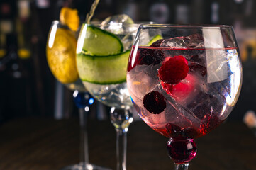 Assorted cocktails with orange, cucumber and berry garnishes served in balloon glasses on a rustic...