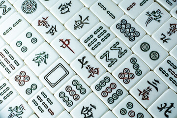 A close-up of a Mahjong tile set, featuring various symbols and characters on white tiles 