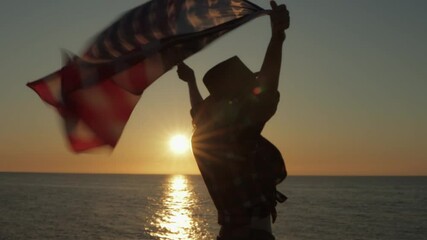 Cowgirl silhouetted against golden sunset, waving american flag on windswept beach, embodying national spirit and freedom.Usa celebrate 4th july. Independence day concept - Powered by Adobe