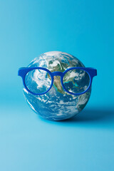 Planet Earth wearing blue glasses on light background. Smart world and environment concept.