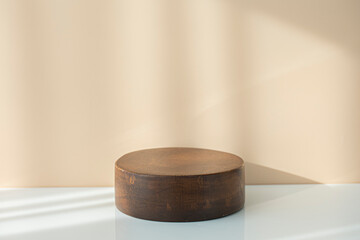 Round wooden podium for food, products or cosmetics against bright brown background.
