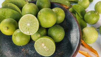 Fresh Green Limes in a Rustic Bowl with Leaves