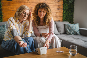 daughter takes care of sick mother with high blood pressure