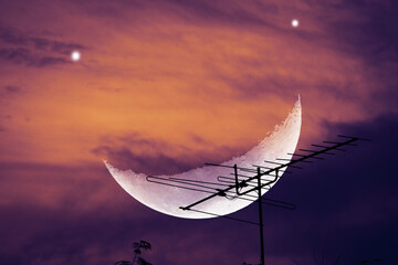 Dramatic Sky with Crescent Moon and Antenna Silhouette at Dusk