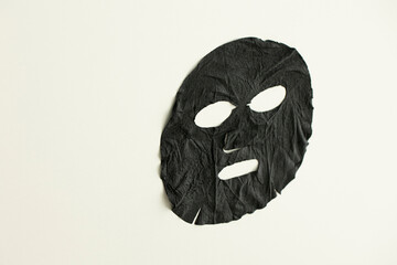 Black sheet mask for skin care on white background.