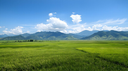 Obraz premium Panoramic View Of Lush Green Fields And Mountains Under A Blue Sky