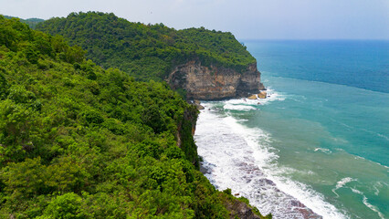 Aerial view of the coast, rocky cliffs and green forests located in Gunung Kidul, Yogyakarta, Indonesia
