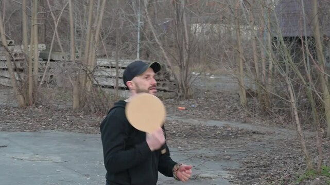 A man with a wooden racket playing sansibar in a forest, ideal for outdoor, sports, and nature themes.