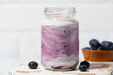 fruit yogurt with blueberries in a glass jar, closeup