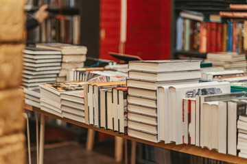 Stacks of hardcover books displayed on bookstore tables during busy literary season. Bookstore...