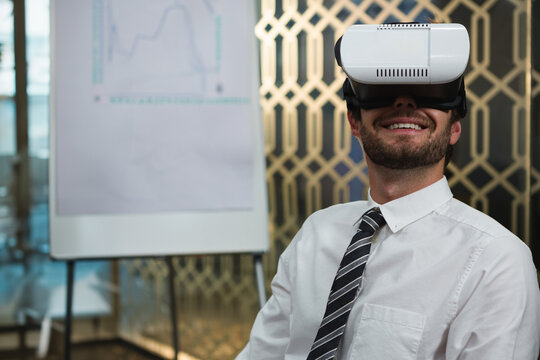 Young professional man using virtual reality headset in office room with flip chart and partition - Powered by Adobe