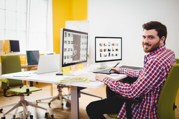 Bearded man using stylus on graphics tablet at modern office, working on digital images, copy space