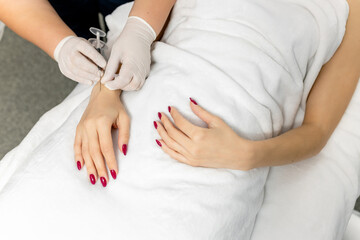 A cosmetologist in white gloves performs mesotherapy, injections of hyaluronic acid into the skin...