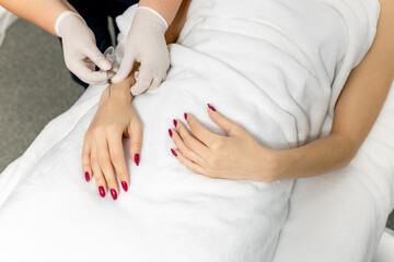 A cosmetologist in white gloves performs mesotherapy, injections of hyaluronic acid into the skin...