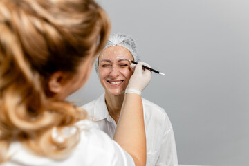 Close-up. Before the procedure for facial contouring or plastic surgery, the cosmetologist makes...