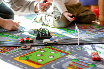Father and son playing with racing cars on racetrack, indoors, with cars. Happy little preschool...