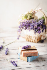 Concept of spa with natural organic oil. Moisturizing skin care and aromatherapy. Gentle body treatment. Handmade soap bars. Atmosphere of harmony, relax. White wooden background, lavender flowers