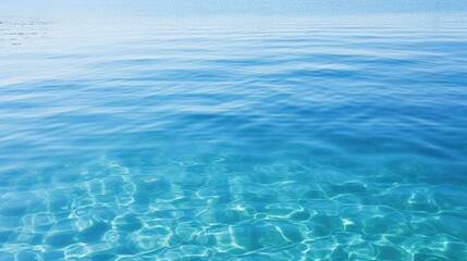 A serene view of calm, clear blue water, reflecting light and creating gentle ripples, evoking a sense of tranquility and peace.