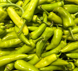 A bunch of green peppers are piled on top of each other