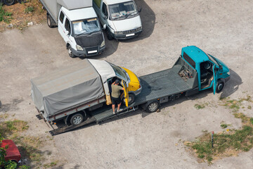 Loading a small inoperable truck onto a tow truck in a parking lot