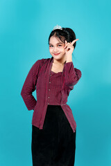 Charming young Asian woman smiling sweetly with confident eye expression and playful finger pose....