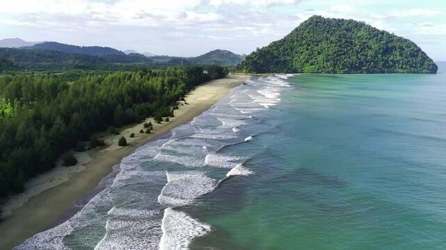 waves with green lush mountain, vegetations and hills under cloudy sky on Geurute Beach