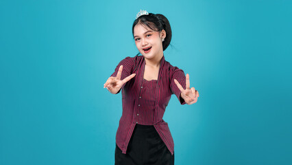 Young Asian woman wearing a tiara showing a cheerful facial expression while making a double peace...