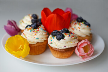 Confectionery products. Cupcakes decorated with cottage cheese cream and tulips. Food and drinks, sweet pastries.