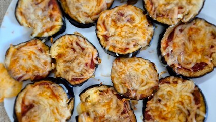 Oven-baked eggplant slices topped with tomato sauce and melted cheese, freshly prepared at home as...
