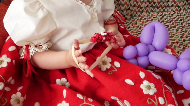 Ni&ntilde;a vestida de huertana juega con un objeto de flores en el d&iacute;a del Bando de la Huerta, fiesta tradicional de las fiestas de primavera de la ciudad de Murcia, Espa&ntilde;a. 