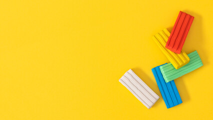 Children's plasticine. Children's colorful plasticine bricks on a yellow background. Creativity children toys concept. Copy space