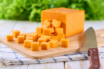 cheddar cheese sliced ​​into cubes on a light kitchen table, selective focus.
