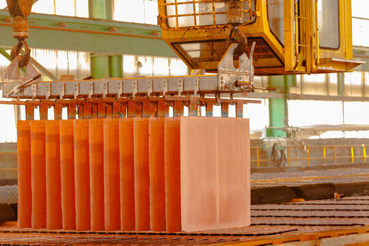 Close-up of copper cathodes hanging from a crane in an electrowinning plant at a copper mine.