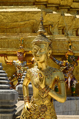 Fototapeta premium The face of golden Kinnari statue at Wat Phra Kaew. Kinnari are half-bird, half-woman creatures from Buddhist mythology. Wat Phra Kaew is a famous tourist attraction in Bangkok capital city, Thailand.