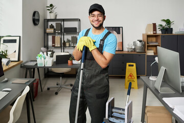 Portrait of cleaning worker in uniform smiling at camera while doing service in office