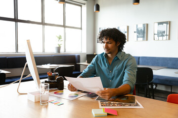 Man reviewing photos and color swatches alongside DSLR camera on creative studio table, copy space