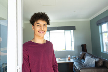 Man standing partially in sliding glass door frame in living room with large window, copy space