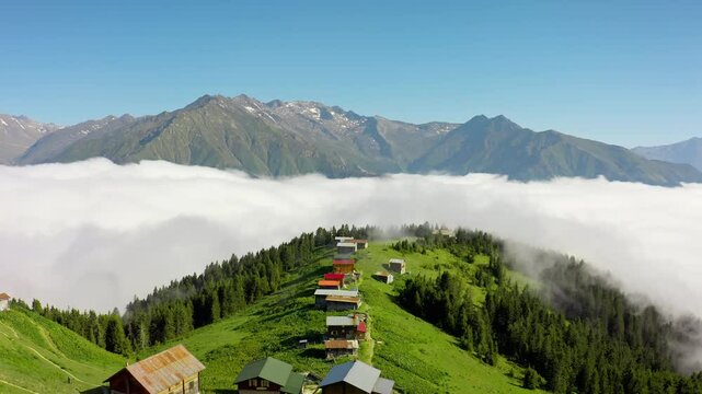 The sea of ​​fog spreading over the lush green hills of Pokut Plateau and the traditional wooden highland houses create a mystical atmosphere. The drone glides into this impressive fog cloud.