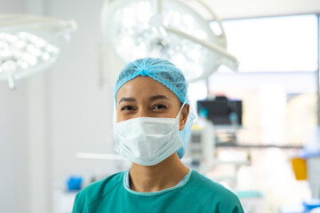 African American woman standing in hospital operating room, featuring surgical lights and monitors
