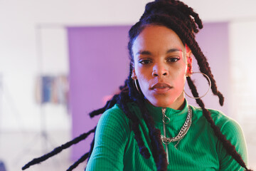 Mid-adult African American woman posing in photo studio with purple backdrop, wearing green top