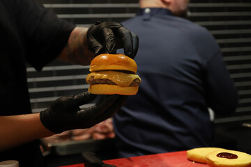 chef enseñando con sus manos una hamburguesa gourmet recién elaborada